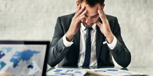 un homme d'affaires se tient la tête sur une table